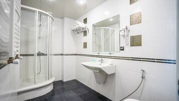 A bathroom with a glass-enclosed shower, a sink with a mirror, and a toilet.