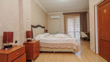 A bedroom with a bed, a nightstand, a dresser, a chair, and an air conditioning unit.
