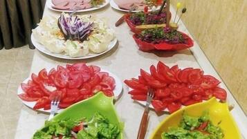 A buffet table with various dishes including salads, sliced tomatoes, and meat.