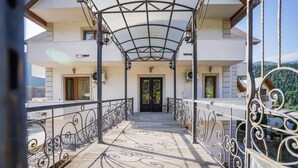 A covered balcony with ornate metal railings, leading to a building entrance. - Natali Hotel (Borjomi)