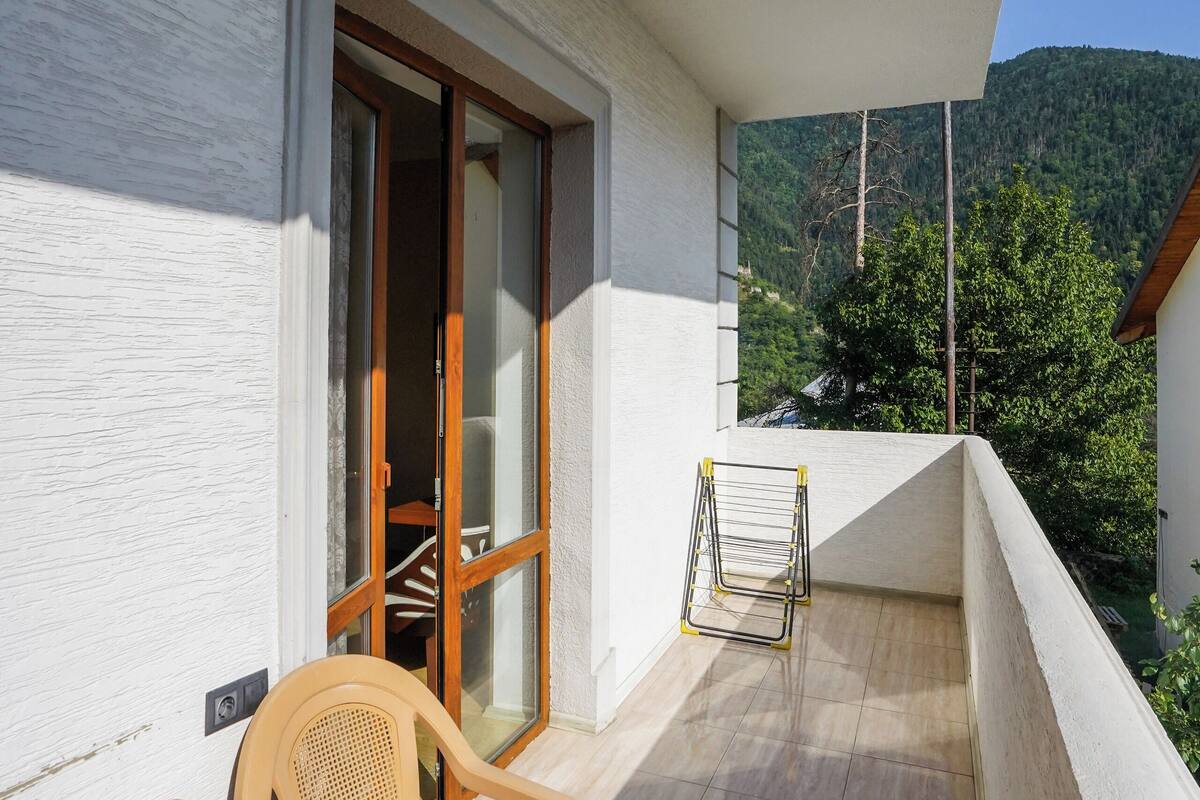A balcony with a table and chairs, a door, and a view of a mountain.