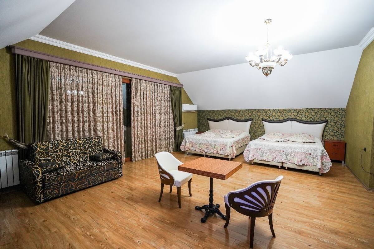 A room with two beds, a sofa, a table, and chairs.