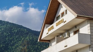 A hotel building with a sloped roof, a balcony, and a mountainous backdrop. - Natali Hotel (Borjomi)