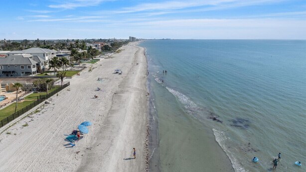 A beach with a long stretch of sand, a few umbrellas, and a few people. - Sunset Retreat| Pool Oasis,Walk to Beach,Billiards (Redington Beach)
