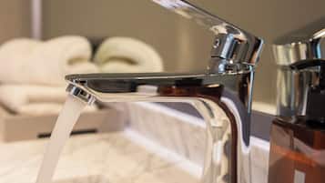 A bathroom with a modern faucet, a marble countertop, and a bottle of JABON LIQUIDO BODY WASH.