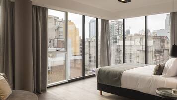 A modern bedroom with a large window, a bed, a bedside table, and a chair.