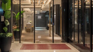 A modern hotel lobby with a reception desk, seating area, and a large potted plant. - Casa Joseph (Buenos Aires)