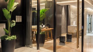 A modern interior with a reception desk, potted plants, and a red mat at the entrance. - Casa Joseph (Buenos Aires)