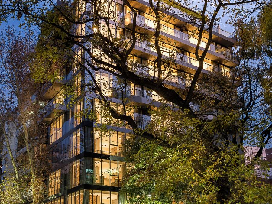 A multi-story hotel with a modern architectural design, featuring balconies on each floor and large windows.