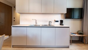 Une cuisine moderne dotée d’un îlot central, de meubles encastrés et d’un téléviseur à écran plat fixé au mur.
