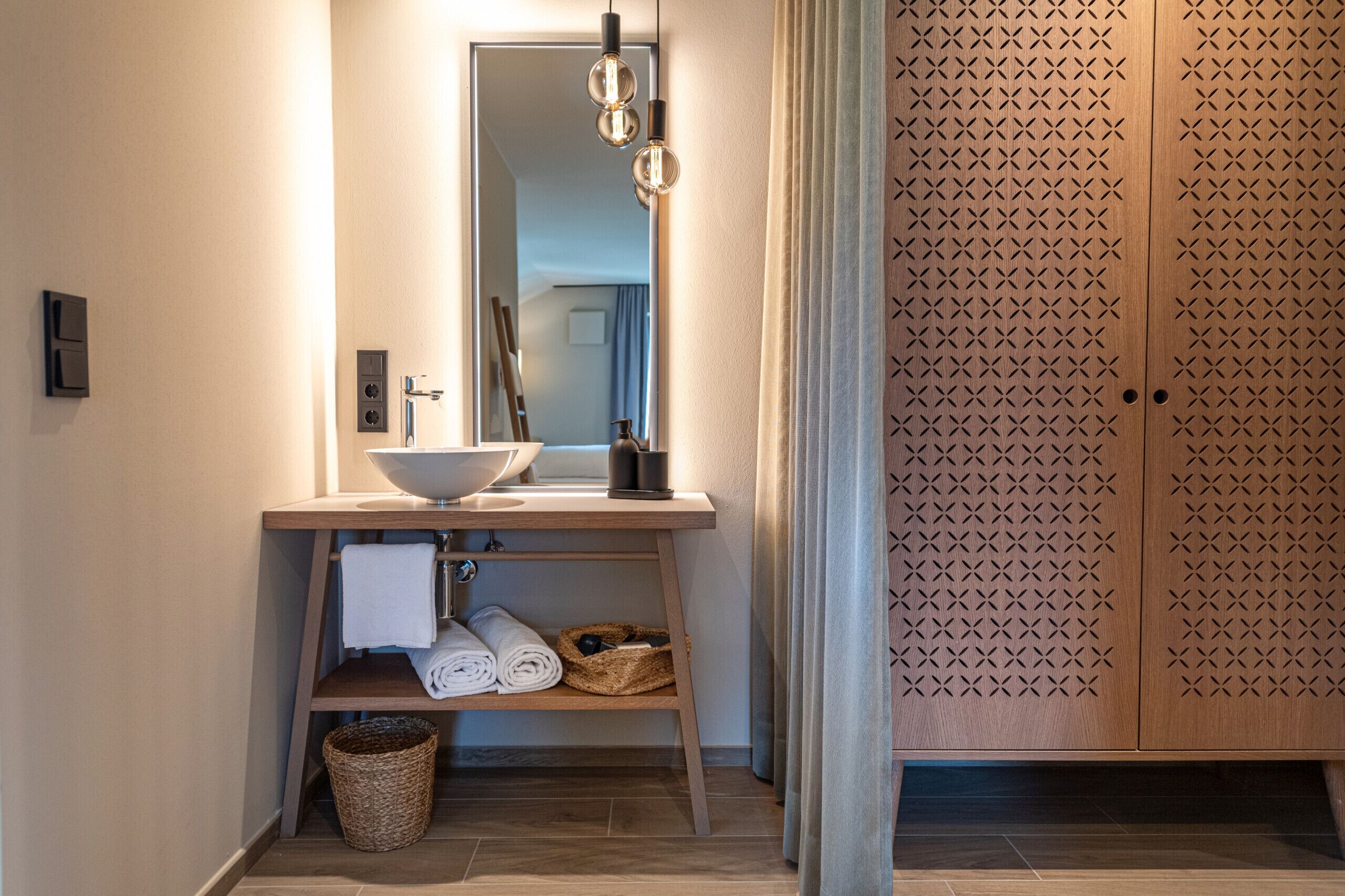 A bathroom with a wooden vanity, a sink, a mirror, and a towel rack.