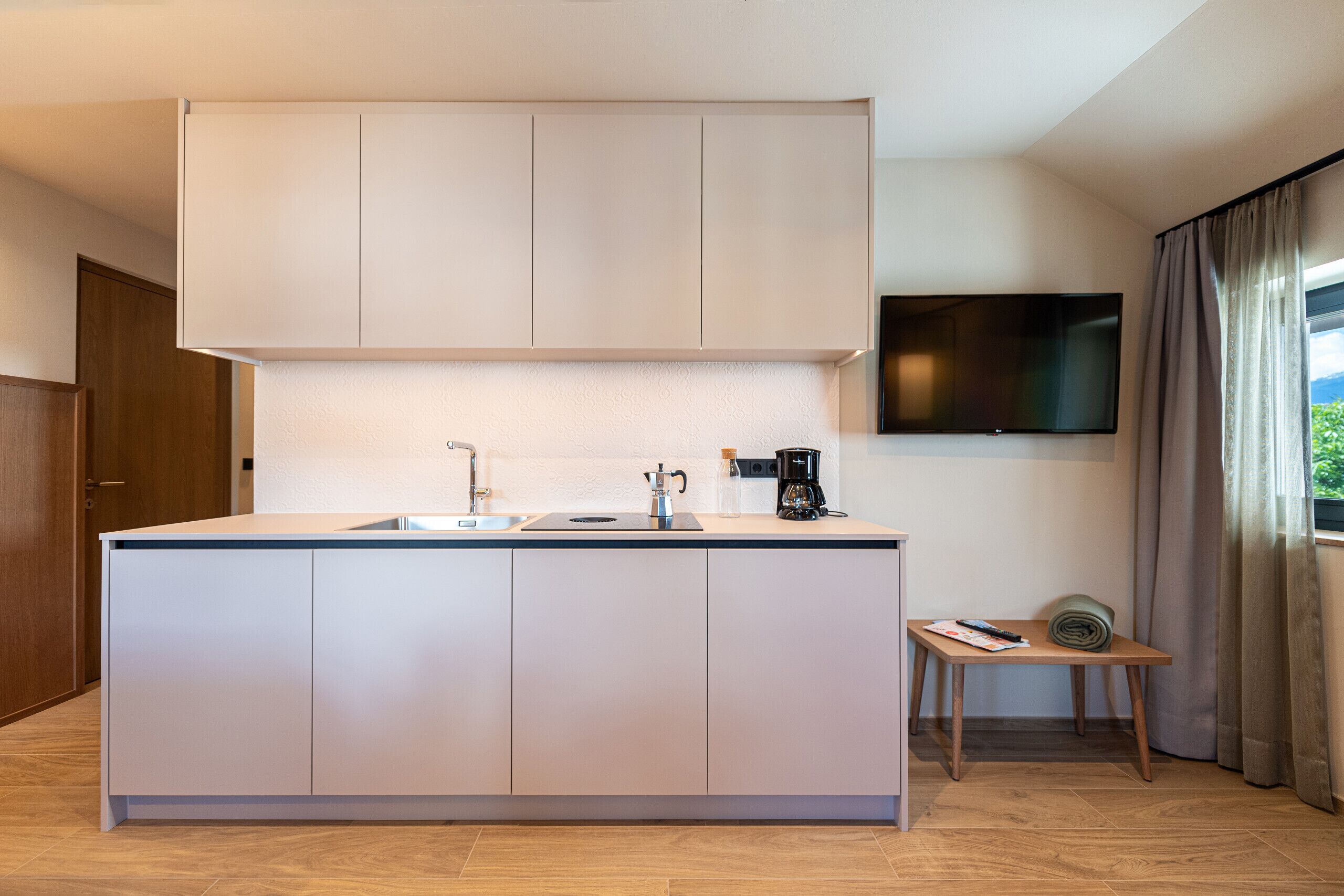 Una cocina moderna con una isla central, horno empotrado y cafetera.