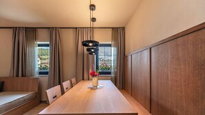 Un espace de salle à manger moderne avec une table en bois, des chaises, un vase de fleurs et une suspension.