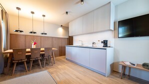 Une cuisine moderne avec des meubles en bois, un îlot central, des luminaires suspendus et un téléviseur à écran plat.