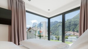 Habitación de hotel con dos camas, ventanas amplias y vistas a un paisaje montañoso.