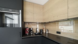 Una cocina moderna con armarios de madera, un refrigerador de acero inoxidable y una cafetera.
