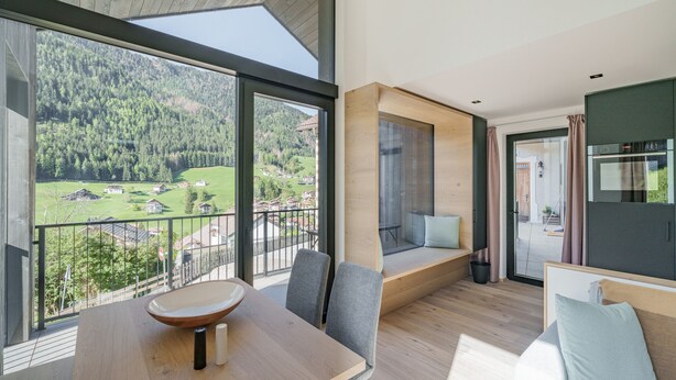 Una habitación moderna con un ventanal grande que ofrece una vista panorámica de un valle boscoso.
