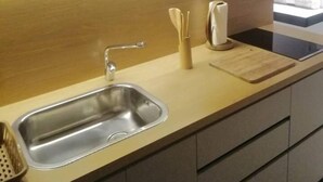 A modern kitchen with a stainless steel sink, a microwave, and wooden cabinets.