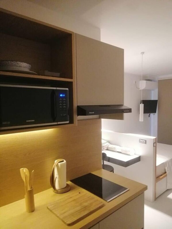Cozinha moderna com micro-ondas, torradeira e tablet sobre a bancada.