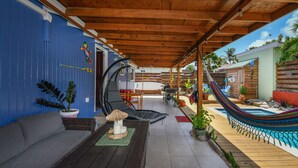 Un patio coperto con un'amaca, posti a sedere all'aperto e una piscina.