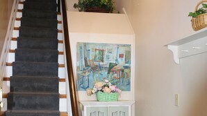 A staircase with a dark carpet and wooden handrail, leading to a white door with a green basket on top. - The 87th House (Portland)