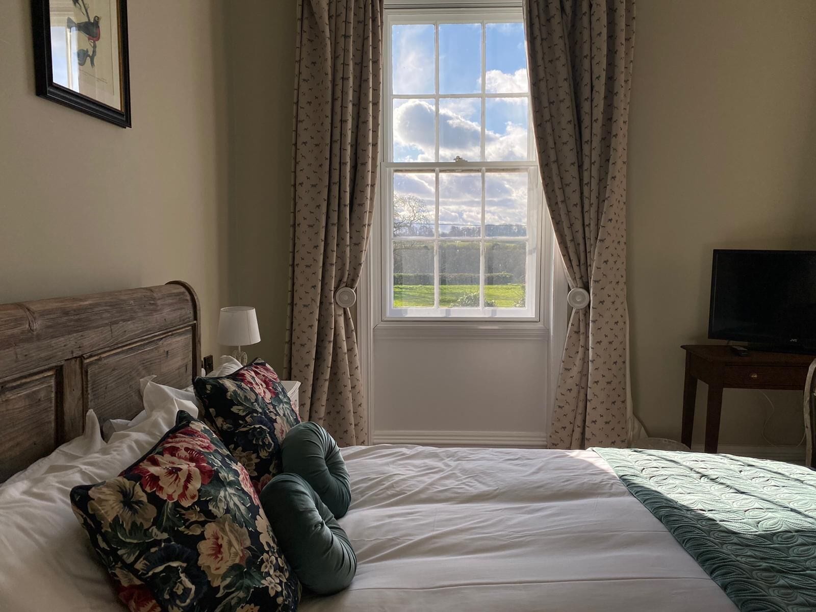 A bedroom with a bed, a TV, and a window with curtains.