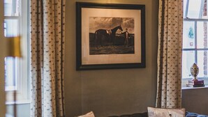 A cozy living room with a framed black and white horse picture on the wall, a leather sofa, and patterned curtains. - The Kedleston Country House (Derby)