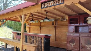 Un bistrot rustique en bois, avec un toit rouge, des bancs en bois et une enseigne sur laquelle on peut lire « BISTROT ».
