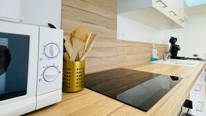 A modern kitchen with a microwave, wooden utensils holder, and a black induction cooktop.