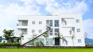 A modern building with a unique zebra mural on the facade, a visible staircase, and a clear sky. - Wunuan ZOO Family Homestay (Jiaoxi)