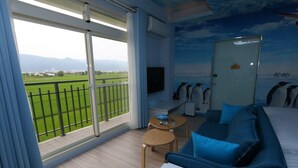 A hotel room with a balcony, a bed, a TV, and a wall mural of penguins. - Wunuan ZOO Family Homestay (Jiaoxi)