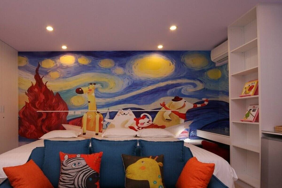Habitación para niños con un mural llamativo, literas y almohadas coloridas.