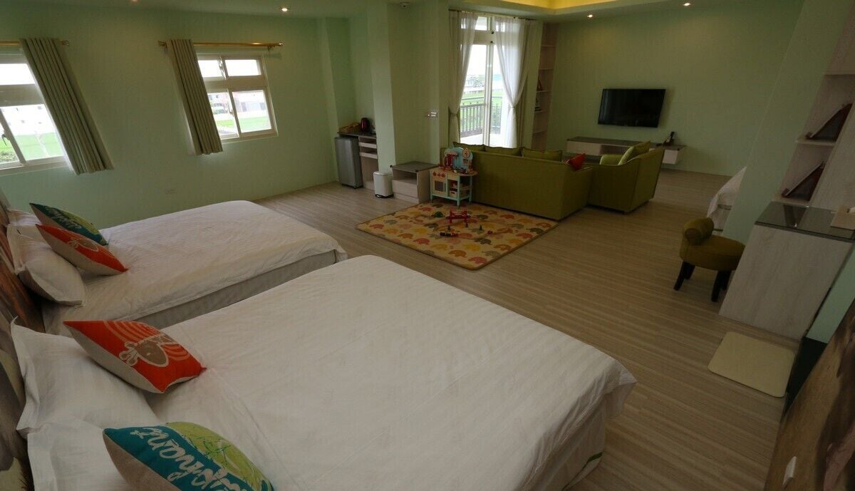 Une chambre d’hôtel avec deux lits, un canapé, une télévision et une petite table.