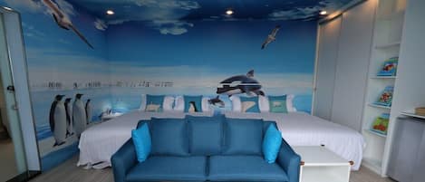 A room with a mural of a beach scene, a bed, a blue sofa, and a small table with toys.
