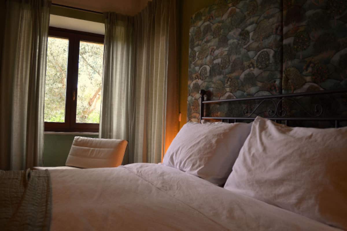Ein Schlafzimmer mit einem großen Bett, einem Fenster mit Vorhängen und einer Wand mit Muster.