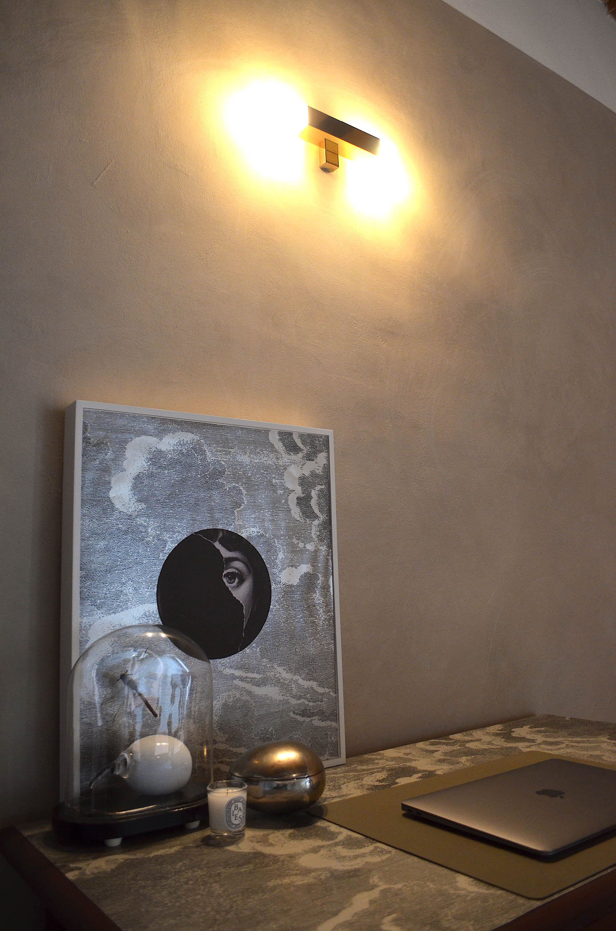 Un bureau avec un ordinateur portable, un objet décoratif en forme de dôme de verre, une bougie et un autre objet décoratif posés sur une surface à motifs.