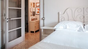 A bedroom with a bed, a nightstand, a dresser, and a door leading to another room. - Bright two-room apartment just minutes from the historic center (Reggio Emilia)