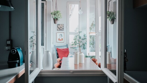 A kitchen with a dining table, chairs, hanging plants, and a view of the outdoors. - Bright two-room apartment just minutes from the historic center (Reggio Emilia)