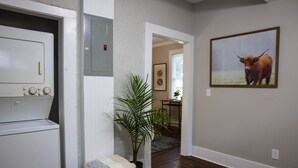 Une buanderie équipée d’un lave-linge, avec une plante et un tableau encadré accroché au mur.