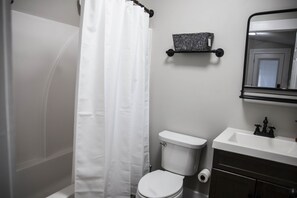 Ein Badezimmer mit Toilette, Waschbecken, Spiegel und Duschvorhang.
