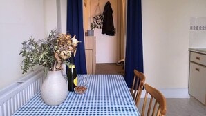 A dining area with a checkered tablecloth, a vase with dried flowers, and a bottle of olive oil. - Cosy 1 Bed Flat Hideout in North London (London)