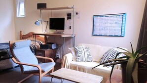 A furnished living room with a desk, a computer, a chair, a sofa, and a potted plant. - Cosy 1 Bed Flat Hideout in North London (London)