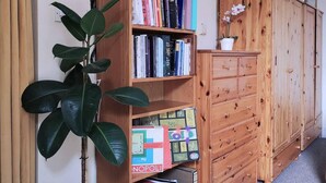 A bookshelf filled with books, a potted plant, and a wooden cabinet with drawers. - Cosy 1 Bed Flat Hideout in North London (London)