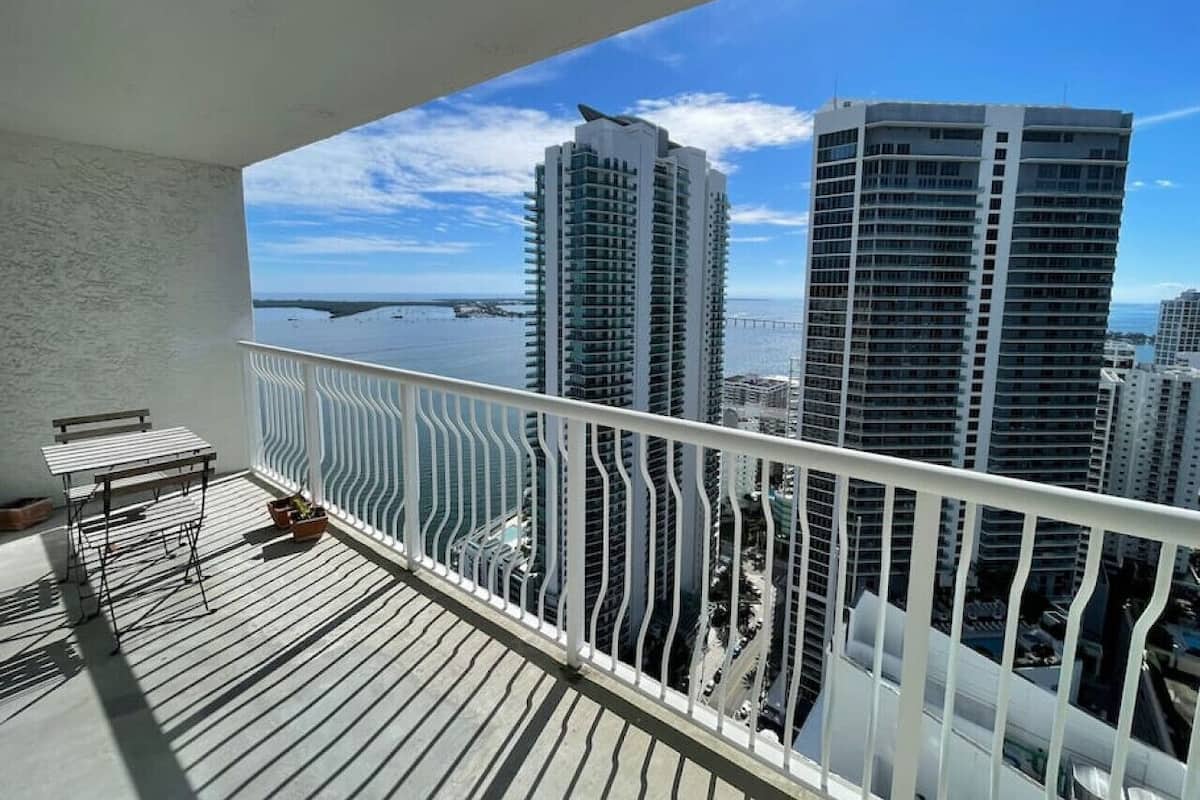 A balcony with a view of tall buildings and a bridge.