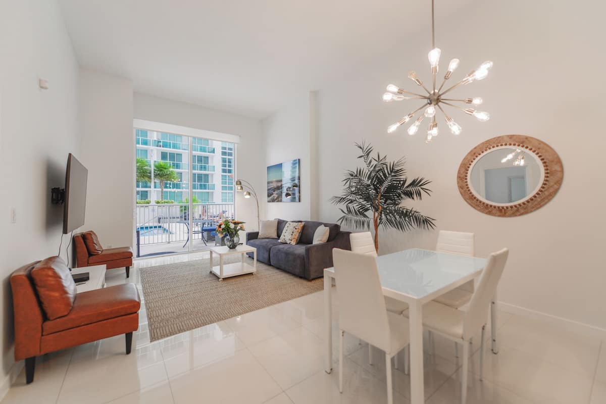 A modern living room with a sofa, coffee table, dining table, and chairs.