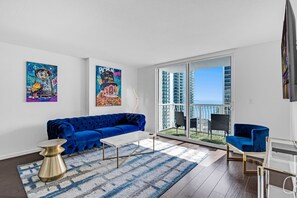 A modern living room with a blue sofa, a coffee table, and artwork on the walls. - The Club at Brickell Bay (Miami)