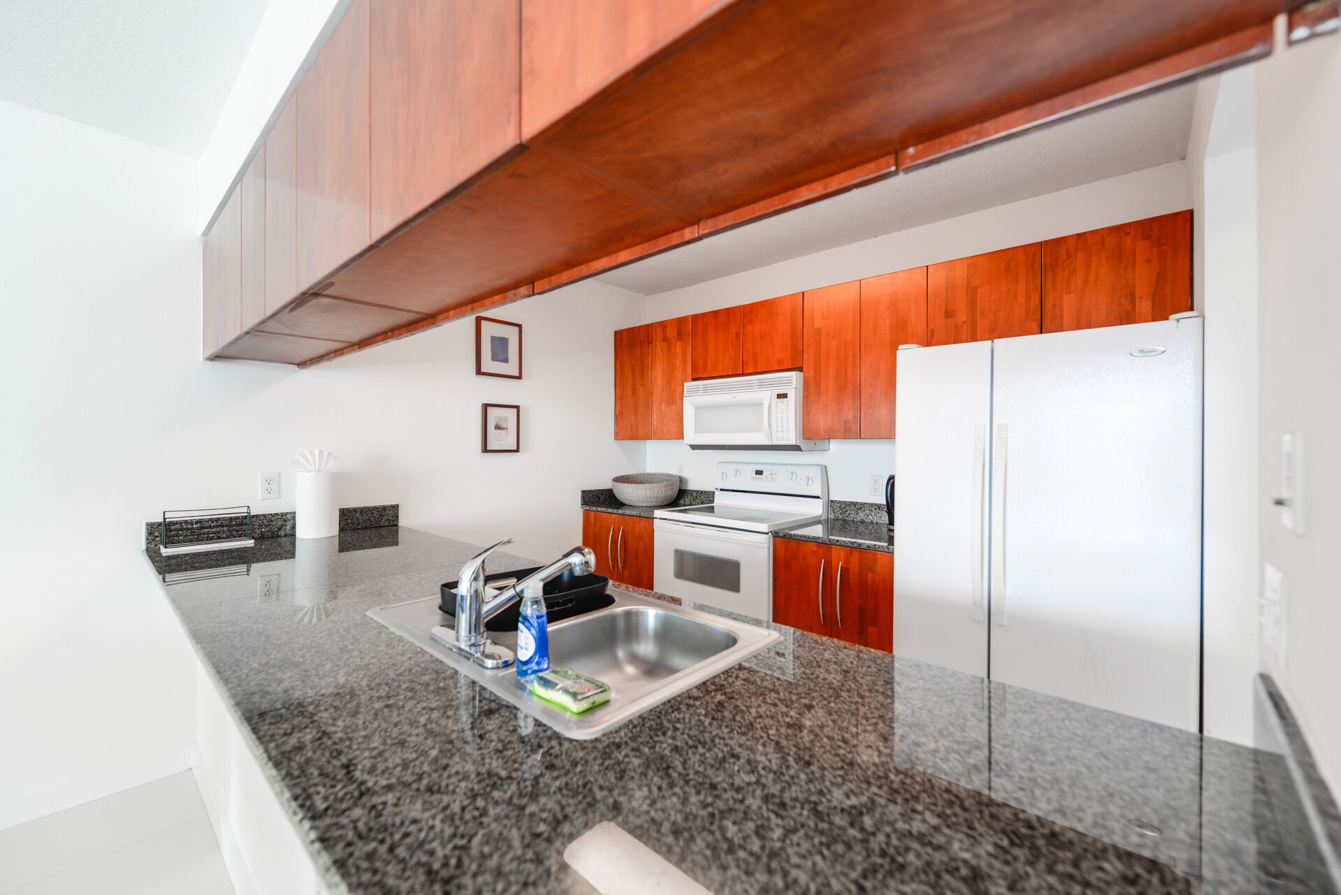 Una cocina moderna con encimeras de granito, electrodomésticos de acero inoxidable y armarios de madera.