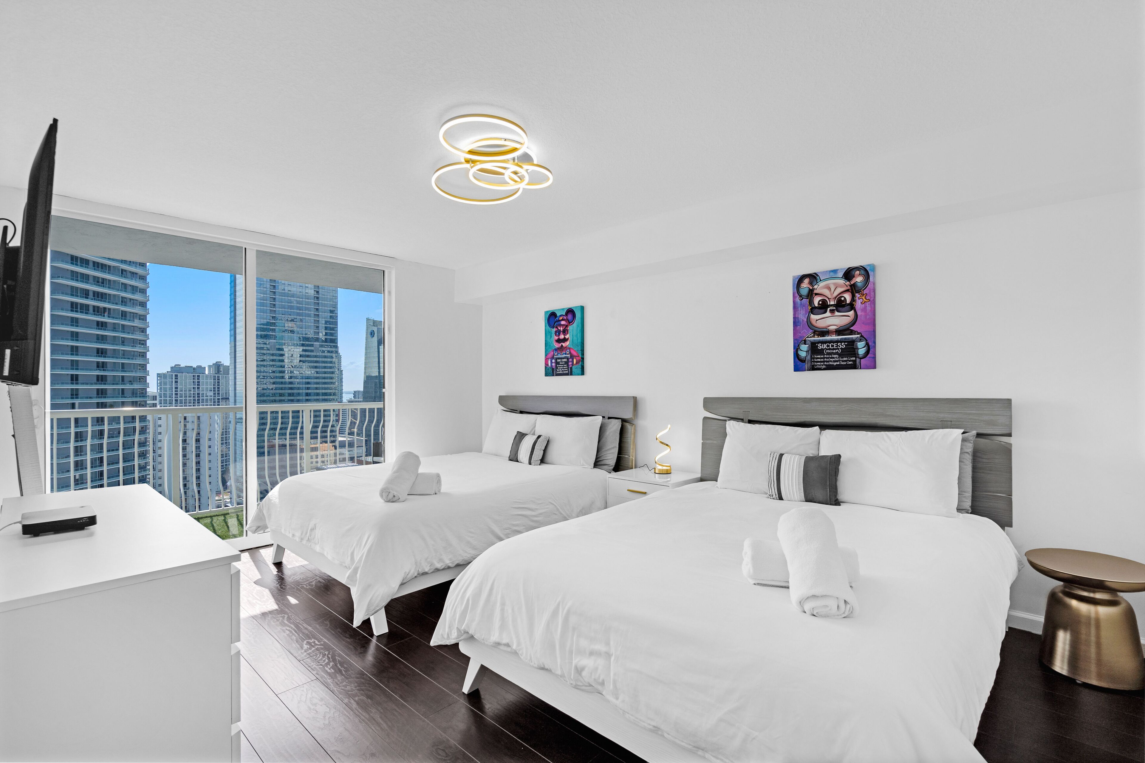 Une chambre d’hôtel moderne équipée de deux lits, d’un bureau et d’une télévision.