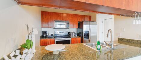 A modern kitchen with wooden cabinets, stainless steel appliances, granite countertops, and a built-in oven.