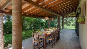 Un área de comedor al aire libre con techo, suelo de ladrillo, mesas y sillas de madera.